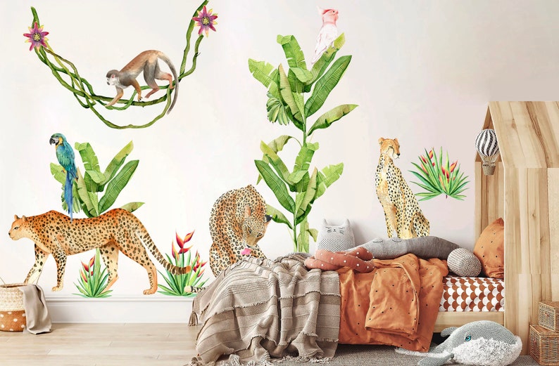 May include: A set of jungle animal wall decals featuring a cheetah, a monkey, a parrot, and a pink bird. The decals are on a white wall with a wooden bed and a brown blanket in the background.