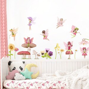 May include: A whimsical wall decal set featuring fairies, flowers, and mushrooms in soft pastel colors. The fairies have delicate wings and are depicted in various poses. The set includes sunflowers, daisies, and pansies, creating a magical, fairytale theme.
