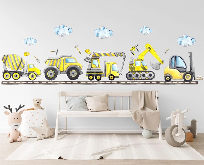 Yellow and gray construction vehicle decals above a bed in a neutral toddler room with plush toys and soft rug