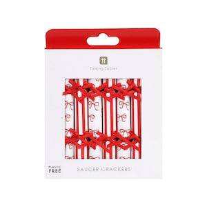 Peut inclure: Une boîte blanche de crackers à soucoupe avec des détails rouges. La boîte a un dessus rouge avec une poignée. Les crackers sont blancs avec des rayures et des nœuds rouges. Le texte "Talking Tables" et "Saucer Crackers" sont visibles.