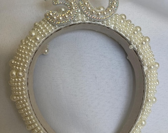 May include: A white headband decorated with white pearls and a pearl-encrusted number "30" on top.