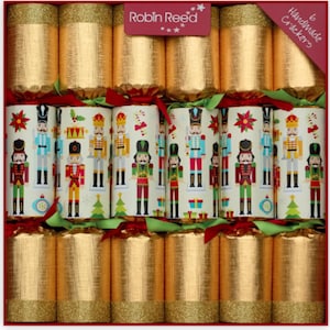 Può includere: Una scatola di sei cracker natalizi fatti a mano. I cracker sono dorati con finitura glitterata. La fila centrale presenta cracker con sfondo crema e illustrazioni colorate di schiaccianoci. La scatola ha un bordo rosso e un'etichetta con la scritta "Robin Reed".
