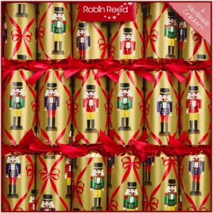 Puede incluir: Una caja de petardos navideños con fondo dorado y lazos rojos. Cada petardo está decorado con un soldado cascanueces de varios colores. La caja tiene el texto "Robin Reed" y "6 Handmade Crackers".