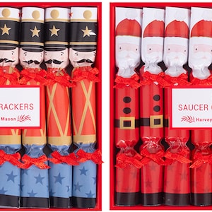 May include: Two boxes of Christmas crackers. One box features toy soldier designs with red, blue, and gold accents. The other box has Santa Claus designs in red and white. Each box contains 8 crackers.