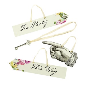May include: Three decorative signs with floral designs and white ribbon loops. The signs read "Tea Party", "This Way", and feature a pointing hand.