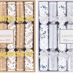 Peut inclure: Deux boîtes de crackers à soucoupe, chacune contenant huit pièces. L'une présente des crackers dorés et blancs avec des nœuds dorés, l'autre des crackers argentés et blancs avec des nœuds argentés. Les boîtes portent une étiquette "8 Saucer Crackers".