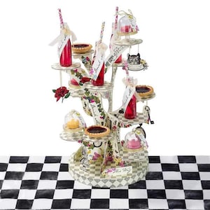 May include: A white cardboard tree-shaped tiered stand decorated with Alice in Wonderland themed graphics. The stand has multiple levels for displaying desserts and drinks. It features a checkered black and white tablecloth.