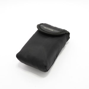 Pode incluir: Uma bolsa protetora retangular preta com fecho de aba. A palavra Kodak está impressa em branco na aba frontal do estojo macio. A bolsa tem uma textura lisa e mate com cantos arredondados, concebida para pequenos dispositivos eletrónicos.