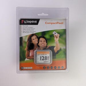 Może przedstawiać: Karta pamięci cyfrowej CompactFlash Kingston w przezroczystym plastikowym opakowaniu. Karta jest oznaczona jako "128MB" i zawiera zdjęcie pary. Opakowanie zawiera również logo Kingston i 5-letnią gwarancję.