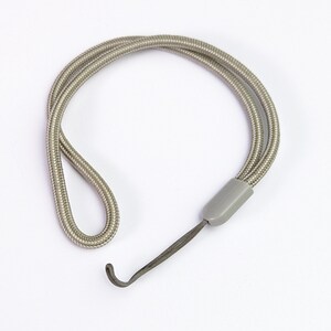 Pode incluir: Um cordão trançado cinza-claro com uma peça de conexão de plástico lisa e arredondada. O cordão é dobrado para formar uma figura circular, com uma extensão de cordão cinza-escuro mais fina presa ao componente de plástico para fixação.