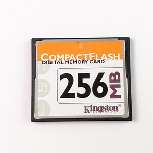 May include: A CompactFlash digital memory card with a black frame and an orange top. The card displays "256 MB" in large black font, with the Kingston Technology logo below. The text "COMPACTFLASH DIGITAL MEMORY CARD" is also visible.