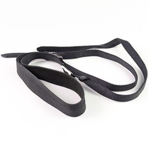 Peut inclure: Une sangle noire en nylon avec une boucle et un design réglable. La sangle est posée sur une surface blanche. La sangle est faite d'un matériau tissé durable et est conçue pour être utilisée avec divers articles.