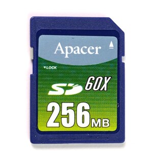 Può includere: Una scheda di memoria SD blu a marchio Apacer con un'etichetta sfumata verde e blu. L'etichetta riporta il testo Apacer, un logo SD bianco, il testo 60X e la capacità 256MB. Un piccolo interruttore di blocco bianco è visibile sul lato sinistro.