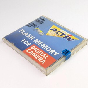 May include: A white ceramic mug with a black handle and the text "But First, Coffee" in a black, bold font. The mug is on a white surface.