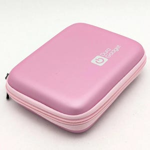May include: A pink Dura Gadget case with a matching pink zipper. The case has a rounded rectangular shape and a white logo on the top. The logo includes a power symbol and the words "Dura Gadget".