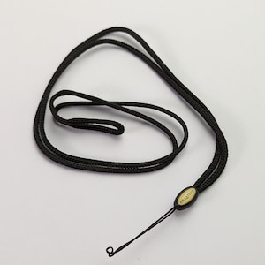 May include: Black lanyard with a braided cord design. The lanyard features a black oval-shaped clasp with the word "CREATIVE" printed in white. The cord is looped and has a small loop at the end.