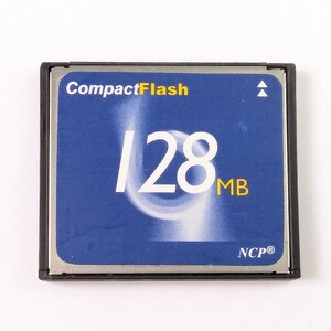 May include: A CompactFlash memory card with a blue face and black frame. The card has the text "CompactFlash" at the top and "128 MB" in large white numbers and letters. The bottom of the card has the text "NCP®".