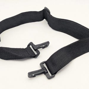Pode incluir: Uma alça de ombro de substituição preta ajustável feita de fita de nylon tecida. A alça possui dois ganchos giratórios de plástico preto em cada extremidade para fixação segura e uma fivela deslizante de plástico para ajustar o comprimento.