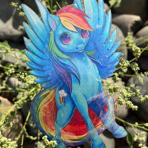 May include: A blue and rainbow-colored cartoon pony with a lightning bolt and cloud symbol on its flank. The pony has large, pink eyes and a rainbow mane and tail. The pony is depicted with wings and is flying.