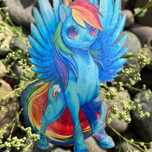 May include: A blue and rainbow iridescent sticker of a cartoon pony with wings and a rainbow mane and tail. The pony has a lightning bolt cutie mark on its flank.