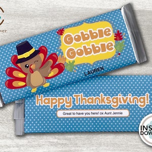 May include: A blue and white polka dot chocolate bar wrapper with a cartoon turkey wearing a pilgrim hat. The wrapper says "Gobble Gobble" and "Happy Thanksgiving!" with the text "Great to have you here! ox Aunt Jennie".