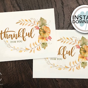 May include: Two cream-colored cards with the words "thankful FOR YOU" in a brown script font. The cards feature a watercolor design of pumpkins, leaves, and branches. A circular "INSTANT DOWNLOAD" graphic is in the upper right.