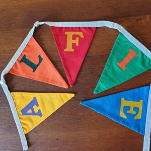 May include: A colourful felt banner with the word "FIFE" spelled out in different coloured letters. Each letter is on a separate triangular flag. The flags are connected by a white string.