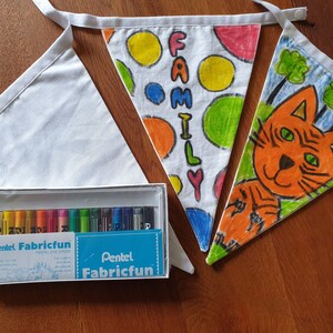 May include: A collection of white fabric bunting, one plain, two decorated with colourful drawings and the word "FAMILY". A box of Pentel Fabricfun pastel dye sticks is also included, ideal for creating custom designs on the bunting.