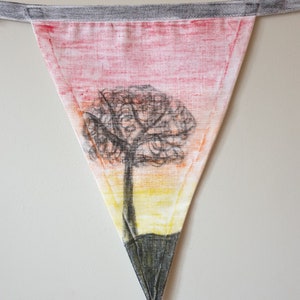 May include: Triangular fabric bunting with a hand-drawn tree design. The bunting features a sunset-coloured background with a black tree silhouette. It is attached to a grey fabric strip for hanging.