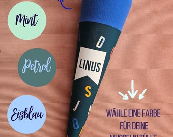 Może przedstawiać: Stożek z ciemnoniebieskiego materiału z napisem "LINUS" i kolorowymi literami. Stożek jest ozdobiony niebieską tkaniną tiulową i białą wstążką. Obraz przedstawia cztery próbki kolorów: miętowy, petrolowy, lodowaty niebieski i królewski niebieski. Pod stożkiem widnieje napis "WÄHLE EINE FARBE FÜR DEINE MUSSELIN TÜLLE".