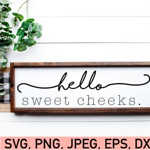 May include: A wooden sign with a white background and a brown frame. The sign says "hello sweet cheeks."