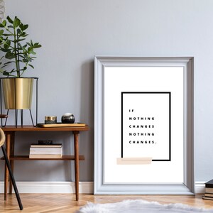 May include: A white framed print with a black rectangle containing the text "IF NOTHING CHANGES NOTHING CHANGES."  The text is in black and the background is white. A light peach coloured rectangle is at the bottom of the print.
