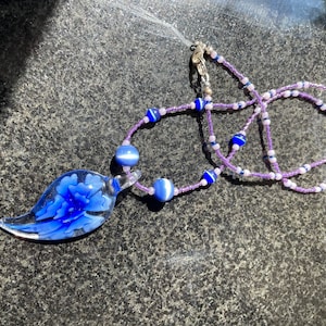 Blue and clear glass pendent with blue accent beads and purple and blue seed beads neckless