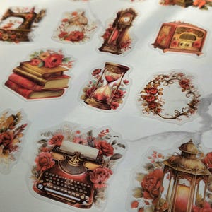 May include: A collection of vintage-themed stickers featuring various designs. The stickers include a red typewriter, an hourglass, a stack of books, a gramophone, a radio, a clock, a birdcage, and a lantern, all adorned with floral accents.