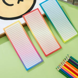 May include: Three lined sticky notes with a gradient of colors, including yellow, pink, and blue. The notes are rectangular and have a white lined interior. A set of colored pencils is in the bottom right corner. The background is a light green.