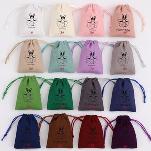 May include: A set of 16 drawstring bags in various colors, each featuring a black and white illustration of a dog inside a box. The bags are numbered 1 through 16.