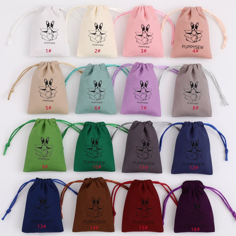 May include: A set of 16 drawstring bags in various colors, each featuring a black and white illustration of a dog inside a box. The bags are numbered 1 through 16.
