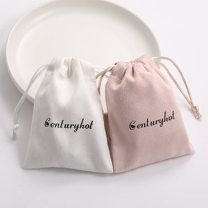 Puede incluir: Dos pequeñas bolsas de cordón, una blanca y otra rosa, con el texto "centuryhot" impreso en cada una.