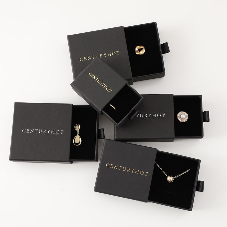 May include: Four black boxes with the text "Centuryhot" printed in gold on the front. Each box contains a different piece of jewelry: a ring, a pair of earrings, a necklace, and a pearl.