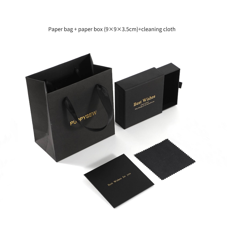 May include: Black gift bag with black ribbon handles and the text "PUPPYSEW" printed in gold. The bag is next to a black gift box with a sliding lid that says "Best Wishes" in gold lettering. A black cleaning cloth and a black card with the text "Best Wishes for you" in gold lettering are also included.