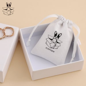 May include: White drawstring bag with a black and white illustration of a French bulldog sitting in a box. The bag has the text "PUPPYSEW" printed on it.