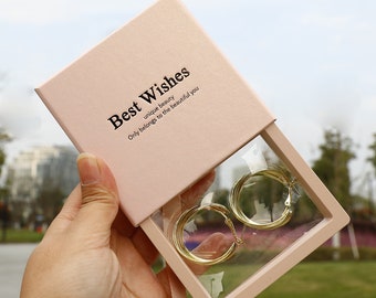 May include: A pink gift box with a clear plastic window, showing a pair of gold hoop earrings. The box has the text "Best Wishes unique beauty Only belongs to the beautiful you" printed on the top.