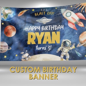 May include: A blue and white space-themed birthday banner with the text "Happy Birthday Ryan turns 3!" and a rocket, astronaut, planets, and stars. The banner is decorated with watercolour illustrations.