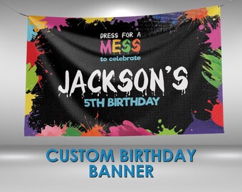 May include: Custom birthday banner with the text "Dress for a Mess to celebrate JACKSON'S 5TH BIRTHDAY." The banner has a black background with colorful paint splatters and the words "CUSTOM BIRTHDAY BANNER" at the bottom.