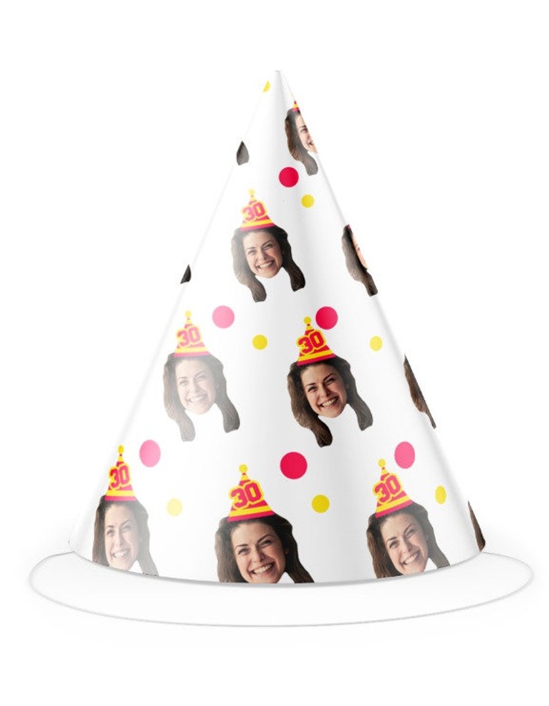 May include: White party hat with a cone shape, adorned with repeating images of a smiling woman. The hat features pink and yellow polka dots and the number "30" on the party hats the woman is wearing.