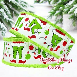May include: Green and red Christmas ribbon with a white background featuring a repeating pattern of the Grinch's legs and feet. The ribbon has a green fuzzy trim. The text "Only Shiny Things On Etsy" is visible in the bottom right corner of the image.