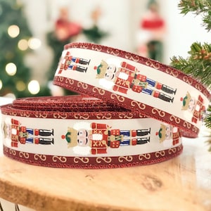 May include: Red and white ribbon with a repeating pattern of nutcracker figurines. The ribbon is rolled up and ready to be used for wrapping gifts or decorating.