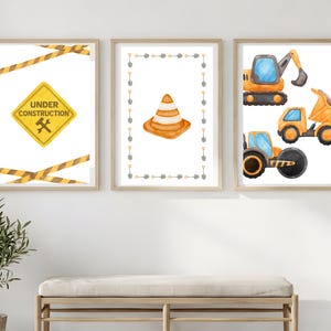 Könnte beinhalten: Drei gerahmte Aquarelldrucke mit Baustellenmotiven. Ein Druck zeigt ein gelbes "Under Construction" Schild mit einem Schraubenschlüssel, umgeben von gelbem und schwarzem Warnband. Ein weiterer zeigt einen orangefarbenen Verkehrskegel, der von Schaufeln umrahmt wird. Der dritte Druck zeigt Baumaschinen.