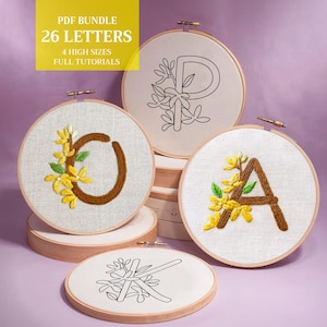 Könnte beinhalten: Stickrahmen mit den Buchstaben O, P, A und K, jeweils mit floralen Akzenten. Der Buchstabe O ist braun mit gelben Blumen. Der Buchstabe P ist schwarz. Der Buchstabe A ist braun mit gelben Blumen. Der Buchstabe K ist schwarz.