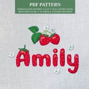 Könnte beinhalten: Stickerei des Namens "Amily" in Rot mit Erdbeerakzenten. Das Design enthält kleine weiße Blüten und zwei Erdbeeren mit grünen Blättern.